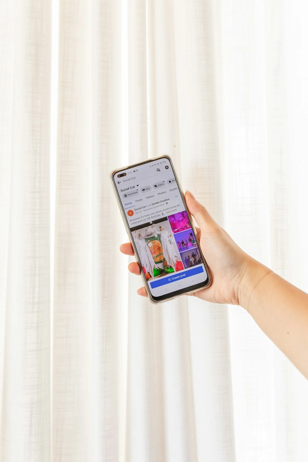 A close-up view of a smartphone screen displaying the email inbox, held by an adults hand.